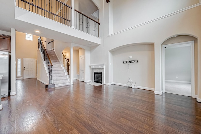 unfurnished living room featuring dark hardwood / wood-style flooring, a tiled fireplace, and a high ceiling