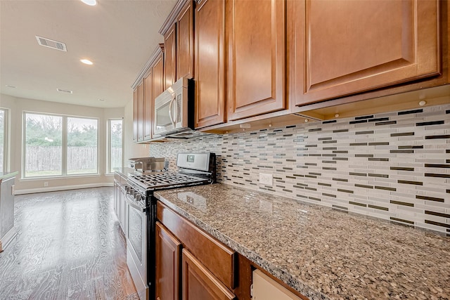 kitchen featuring decorative backsplash, light wood-type flooring, light stone countertops, and appliances with stainless steel finishes