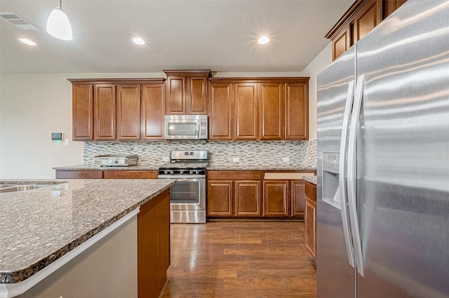 kitchen featuring pendant lighting, sink, dark wood-type flooring, appliances with stainless steel finishes, and backsplash