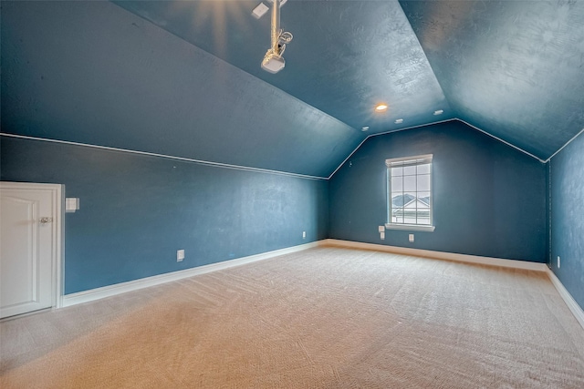 additional living space featuring carpet floors, vaulted ceiling, and a textured ceiling