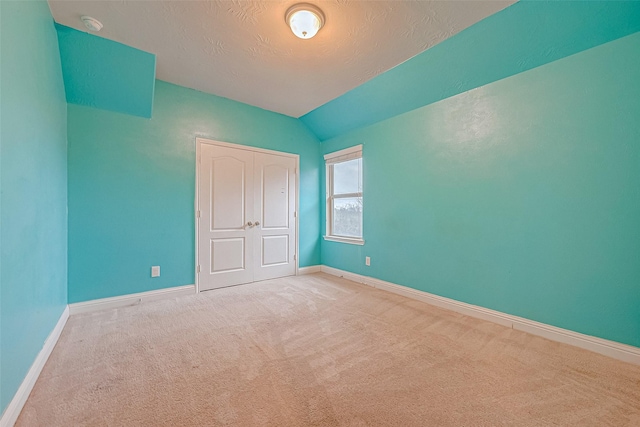 unfurnished bedroom featuring lofted ceiling, a textured ceiling, and carpet flooring