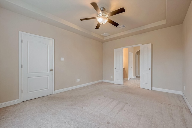 carpeted spare room with ceiling fan and a raised ceiling