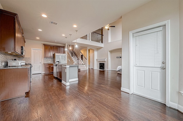 kitchen featuring pendant lighting, an island with sink, dark hardwood / wood-style flooring, decorative backsplash, and stainless steel appliances