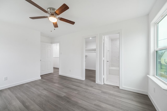 unfurnished bedroom with hardwood / wood-style floors, a spacious closet, ensuite bath, and a closet