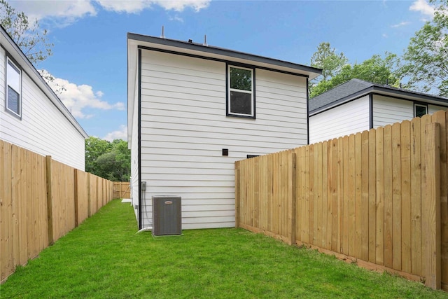 rear view of house with a yard and central AC