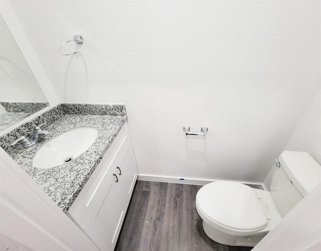 bathroom with wood-type flooring, vanity, and toilet