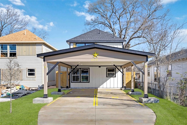 view of front of property with board and batten siding, a front yard, concrete driveway, and fence