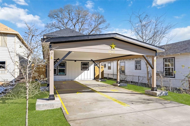 view of front of home featuring driveway, an attached carport, fence, board and batten siding, and a front yard