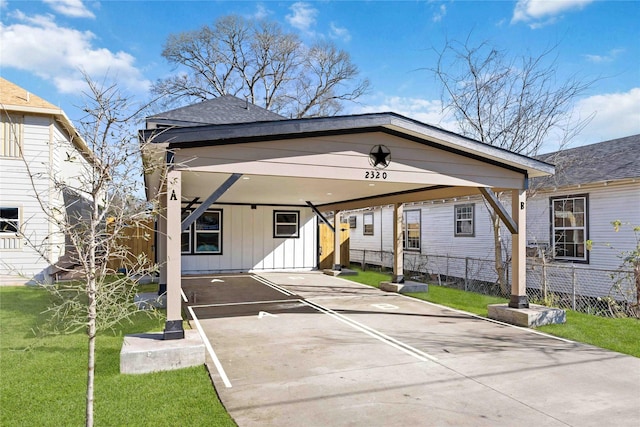 view of front of house featuring fence, concrete driveway, a carport, board and batten siding, and a front yard