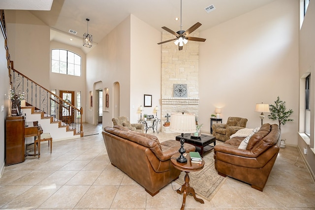 living room with a towering ceiling, a fireplace, ceiling fan, and light tile patterned flooring