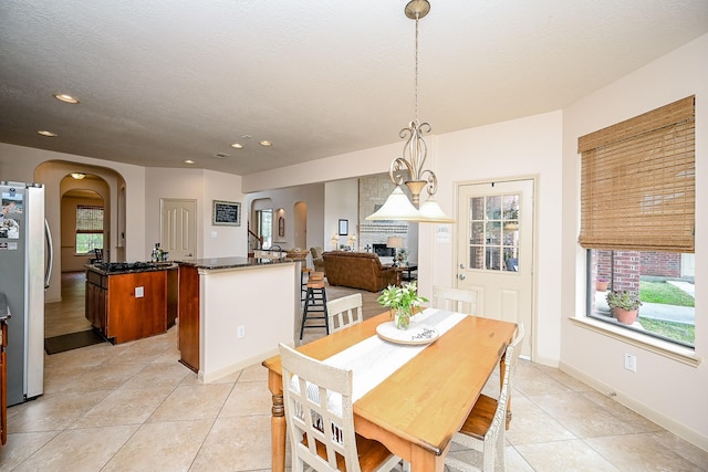 tiled dining area with a healthy amount of sunlight, a large fireplace, and a textured ceiling