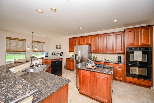 kitchen featuring pendant lighting, tasteful backsplash, sink, black appliances, and a center island with sink