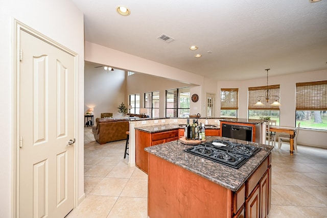 kitchen featuring decorative light fixtures, dark stone countertops, kitchen peninsula, a kitchen island, and black appliances