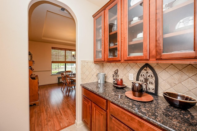 kitchen with backsplash, light wood-type flooring, and dark stone countertops