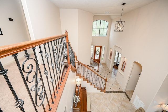 stairway with tile patterned floors and a high ceiling