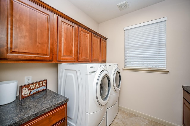 laundry area with independent washer and dryer, light tile patterned floors, and cabinets