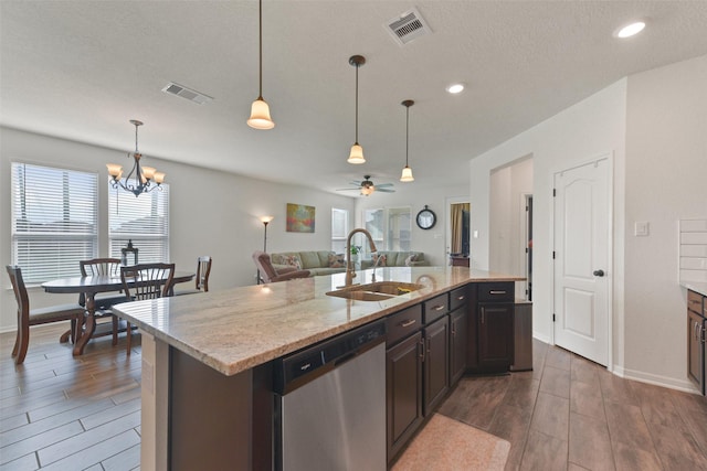 kitchen featuring a kitchen island with sink, dishwasher, sink, and hanging light fixtures