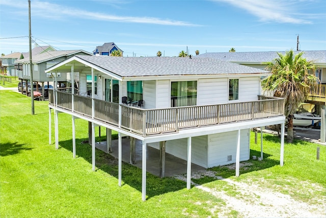 back of house with driveway, a shingled roof, a deck, and a lawn