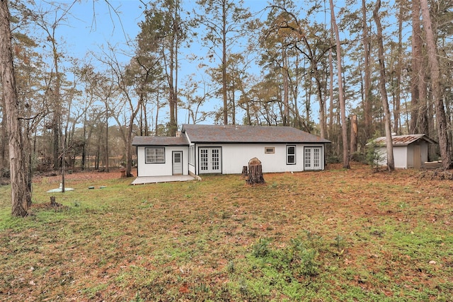 single story home featuring french doors, a storage unit, a patio area, and a front yard