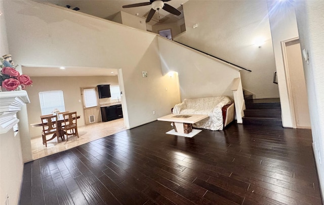 sitting room with a towering ceiling, dark wood-type flooring, and ceiling fan