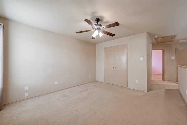 unfurnished bedroom featuring ceiling fan, light colored carpet, a closet, and a textured ceiling