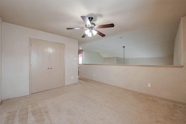 unfurnished bedroom featuring ceiling fan, a closet, vaulted ceiling, and light carpet