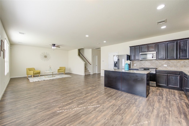 kitchen featuring a kitchen island, appliances with stainless steel finishes, backsplash, dark hardwood / wood-style flooring, and ceiling fan