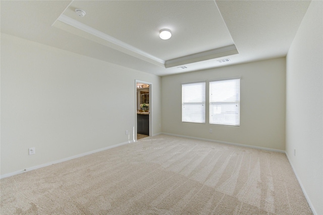 carpeted spare room featuring ornamental molding and a raised ceiling