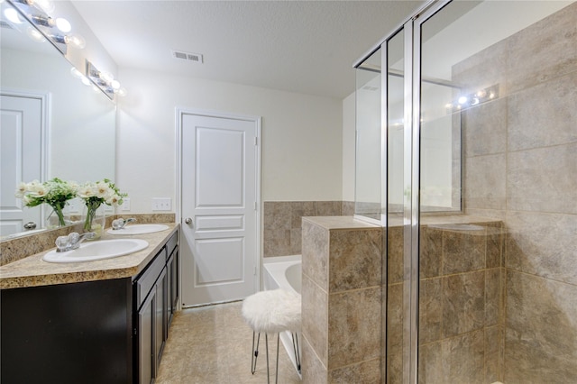 bathroom with vanity, separate shower and tub, and a textured ceiling