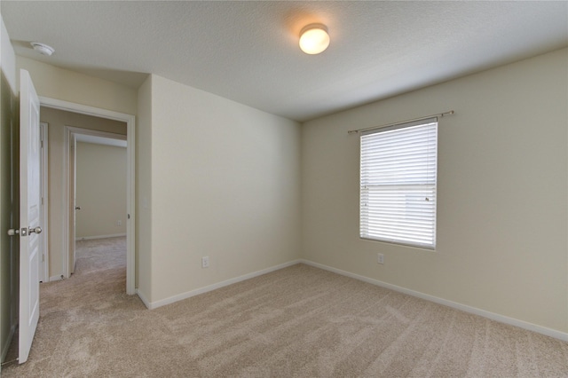 unfurnished room with light colored carpet and a textured ceiling