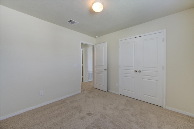 unfurnished bedroom with light carpet and a closet