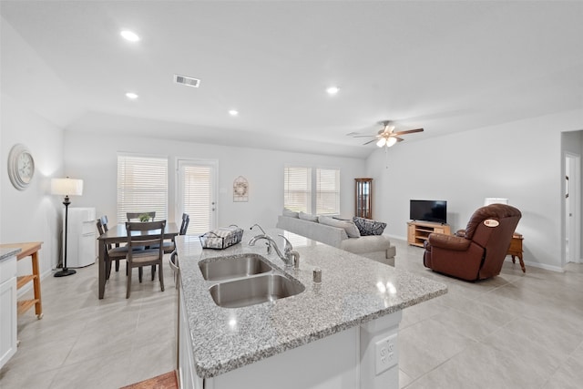 kitchen featuring light stone counters, sink, white cabinetry, and a kitchen island with sink