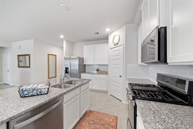 kitchen featuring white cabinetry, sink, decorative backsplash, stainless steel appliances, and light stone countertops