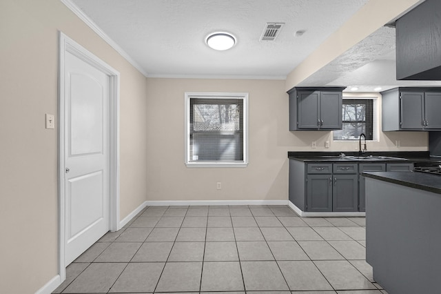 kitchen with gray cabinets, sink, ornamental molding, light tile patterned floors, and a textured ceiling