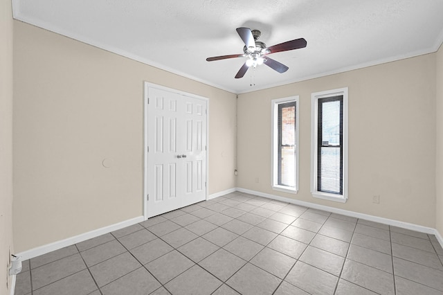 empty room featuring ceiling fan, ornamental molding, a textured ceiling, and light tile patterned floors