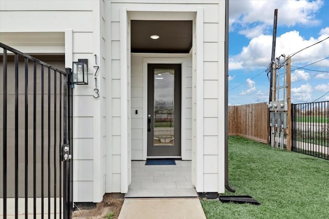 view of exterior entry featuring a lawn