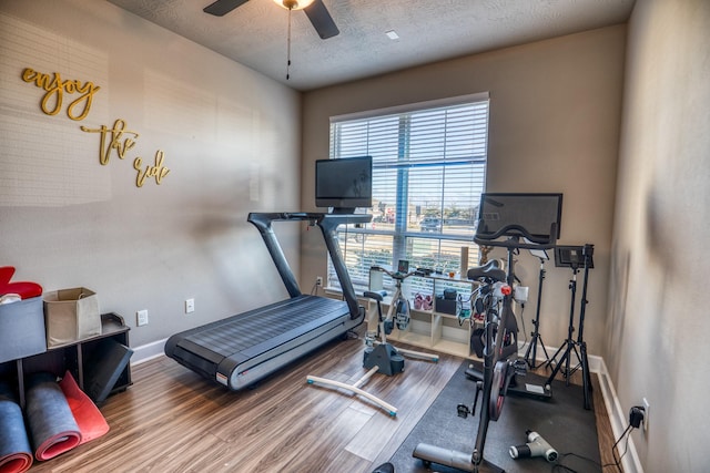 exercise room featuring wood-type flooring, ceiling fan, and a textured ceiling