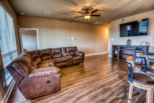 living room with a textured ceiling, wood-type flooring, and ceiling fan