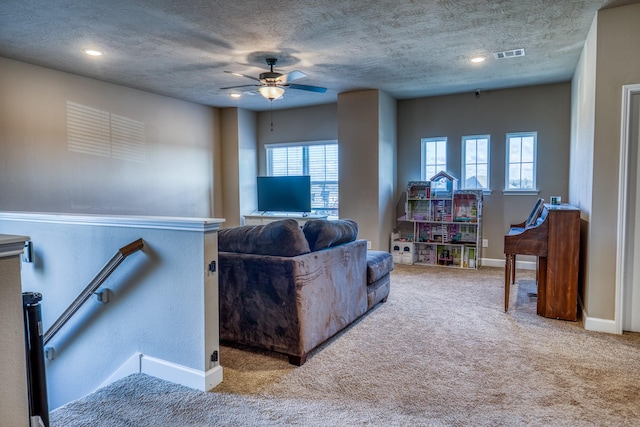 carpeted living room featuring ceiling fan and a textured ceiling