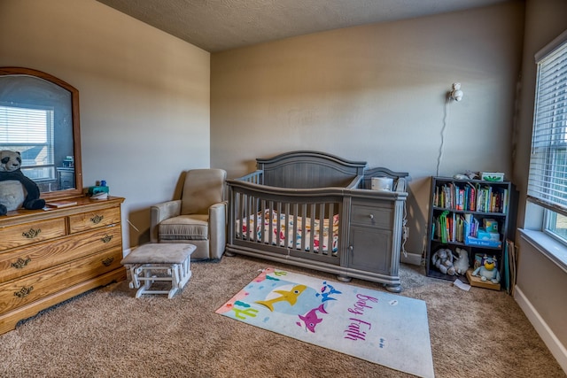 carpeted bedroom featuring a crib and a textured ceiling