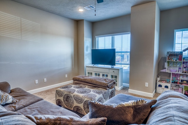 carpeted living room featuring ceiling fan, a textured ceiling, and a wealth of natural light