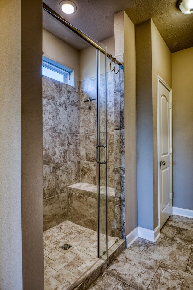 bathroom featuring a shower with door and a textured ceiling