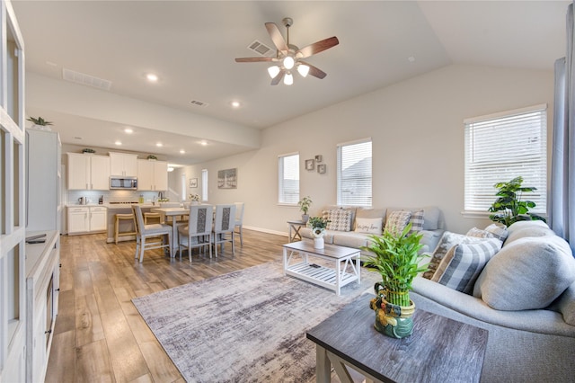 living room with ceiling fan, lofted ceiling, and light hardwood / wood-style floors