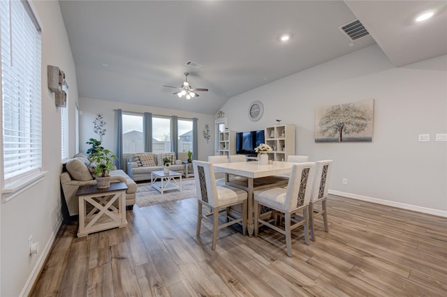 dining area with vaulted ceiling, ceiling fan, and light wood-type flooring