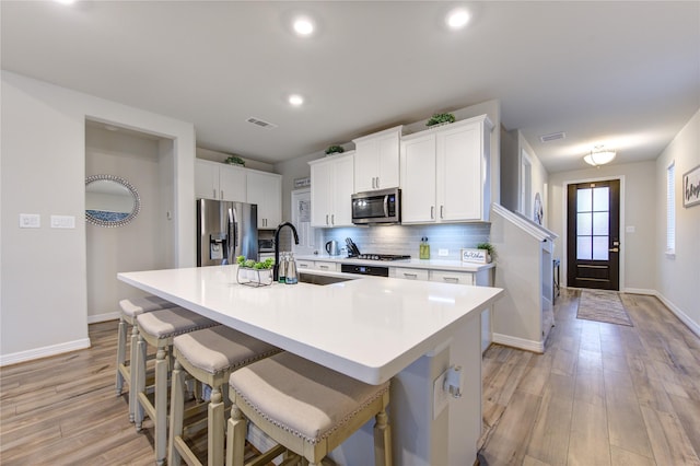 kitchen featuring sink, an island with sink, white cabinets, and appliances with stainless steel finishes