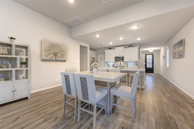 dining space with sink and light wood-type flooring