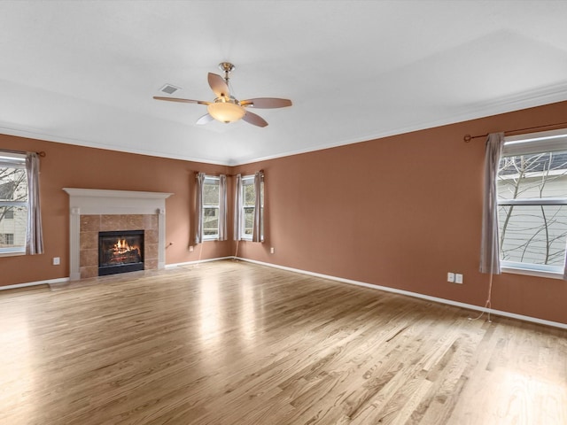 unfurnished living room with a tile fireplace, crown molding, ceiling fan, and light hardwood / wood-style flooring