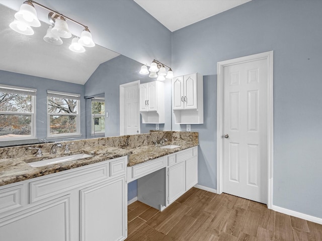 bathroom with wood-type flooring, vaulted ceiling, and vanity