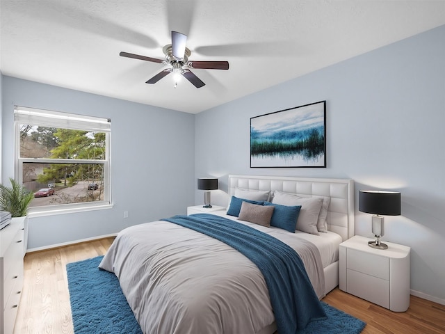 bedroom with a ceiling fan, baseboards, and wood finished floors