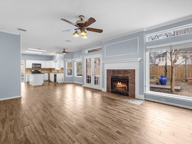 unfurnished living room with crown molding, a fireplace, french doors, and hardwood / wood-style flooring